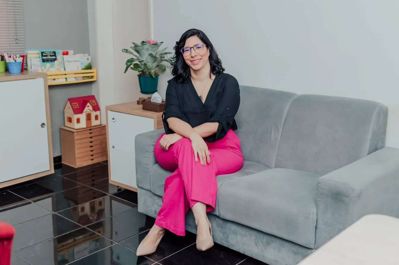 Veruska Veloso sentada no sofá do consultório, sorrindo
